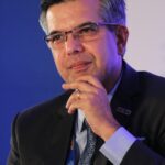 Portrait of a thoughtful businessman in a suit, wearing eyeglasses, captured in an indoor corporate setting.